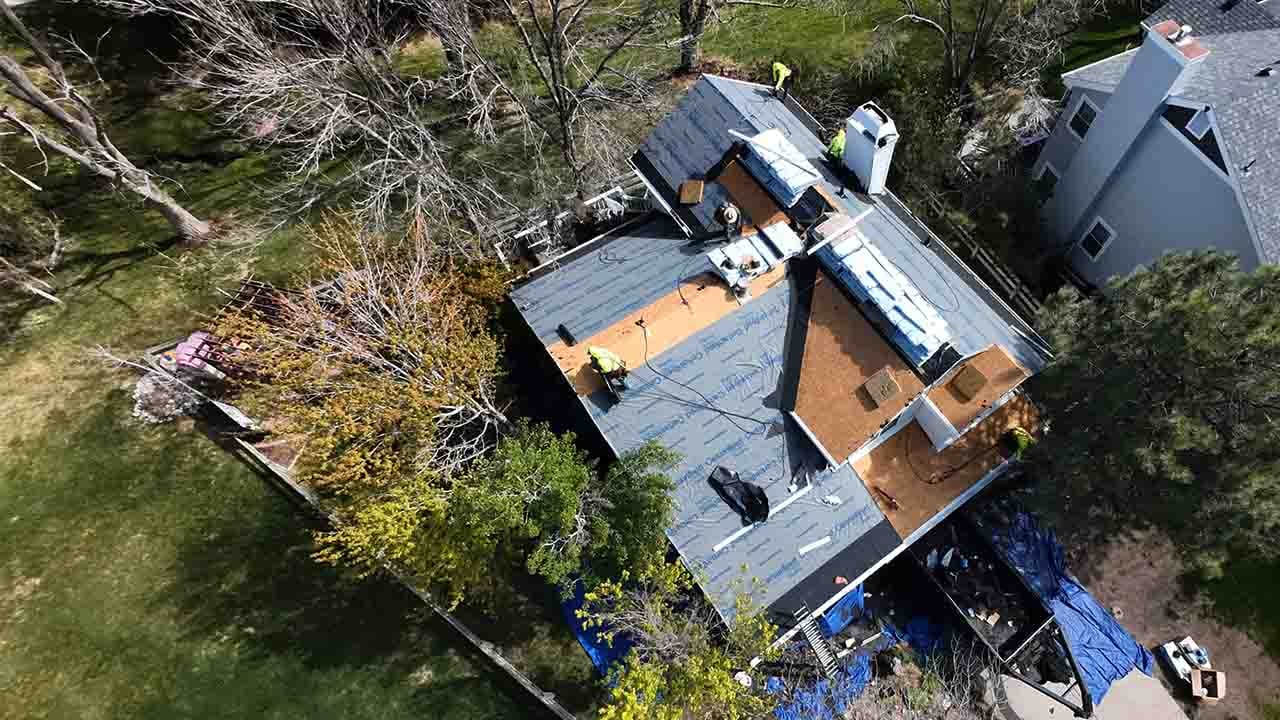 A roof replacement in progress, using presidential asphalt shingles. Workers in yellow high visibility shirts working hard