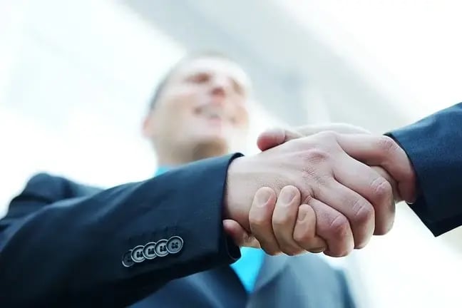 Business shaking hands in front of modern building with copy space (selective focus)-1