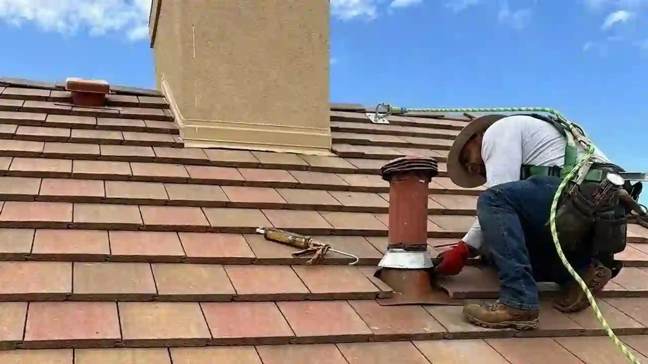 Expert Excel Roofing Repair Technician Raul Repairing Flashing on a Terra Cotta Colored Concrete Tile Roof