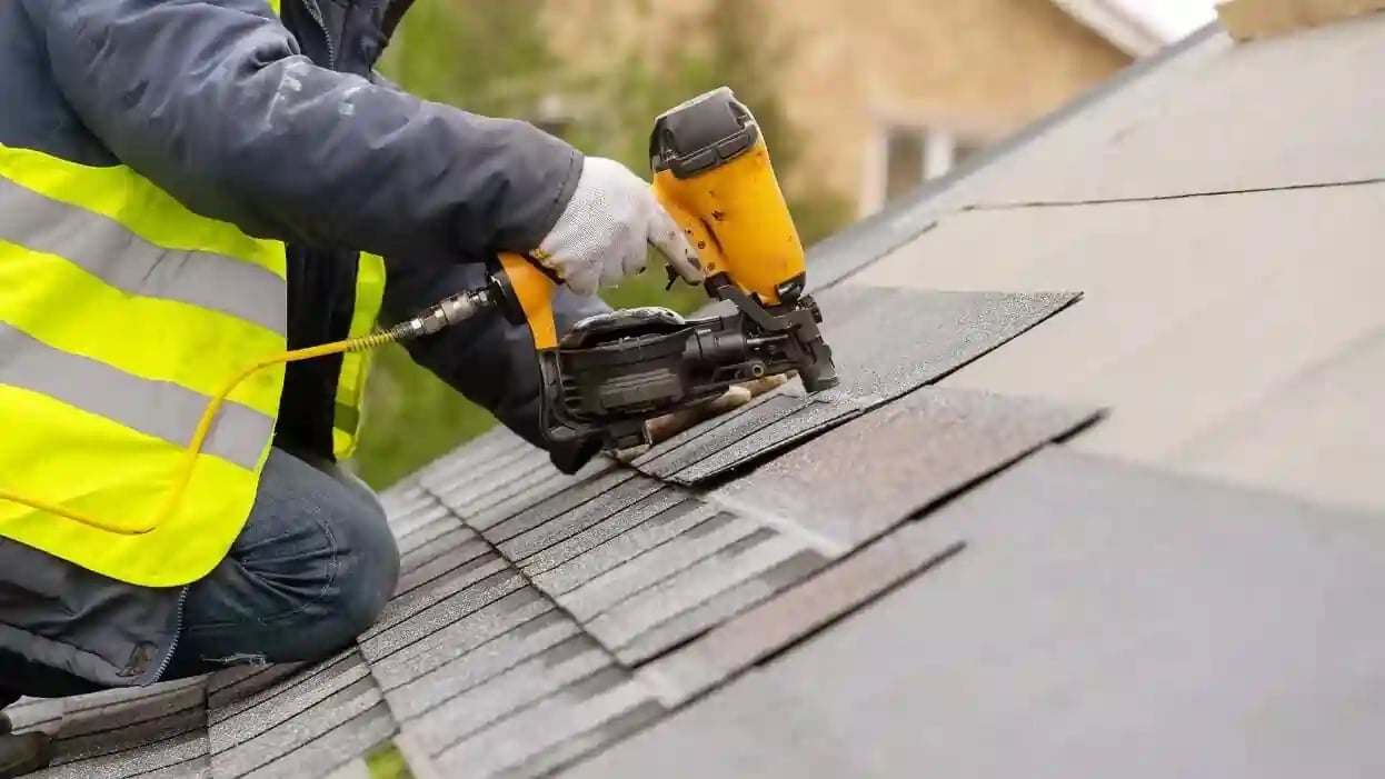 Excel Roofing contractor using a nail gun to secure asphalt shingles