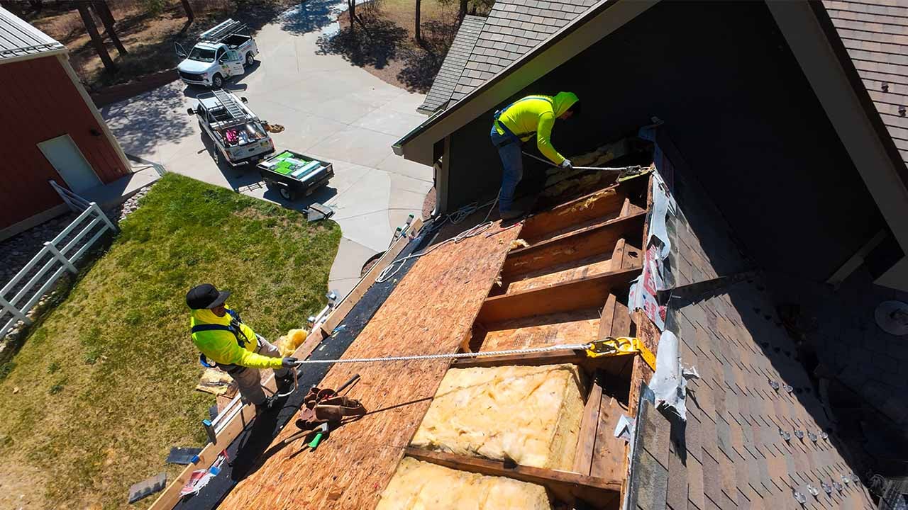 Mario and Alvaro of Excel Roofings Service Team, wearing yellow high visibilty shirts and tied off to the roof Repairing a synthetic tile roof