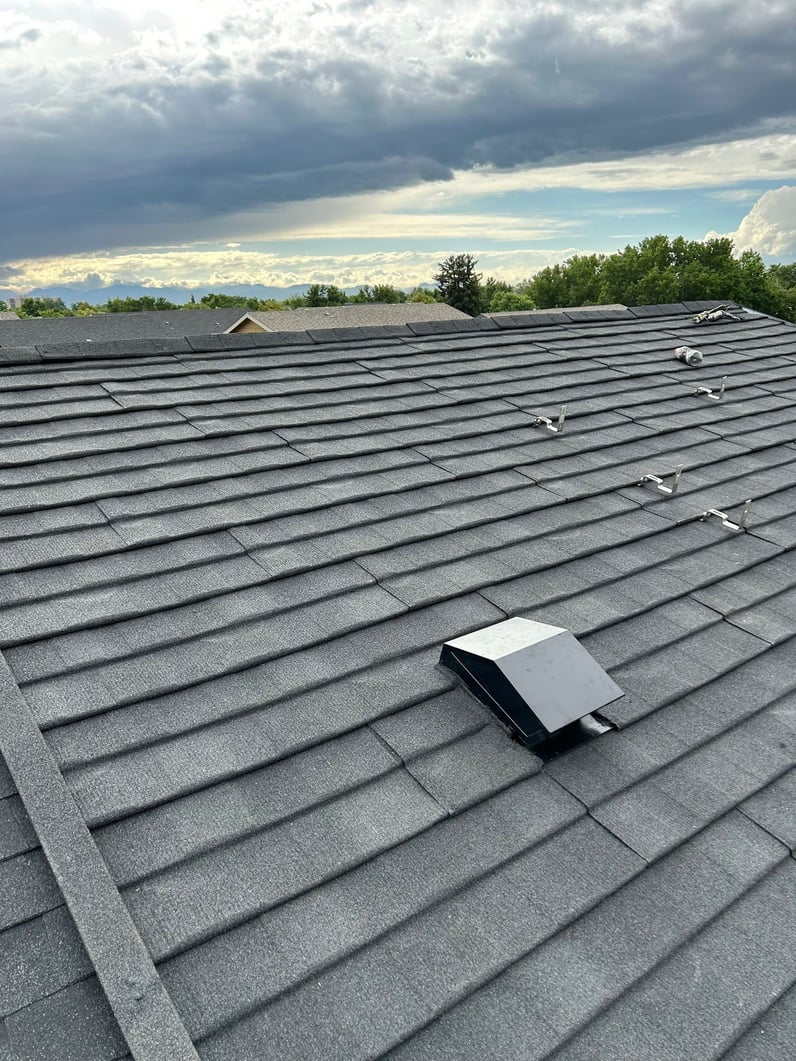 A slate gray stone coated steel roof in front of an on coming storm