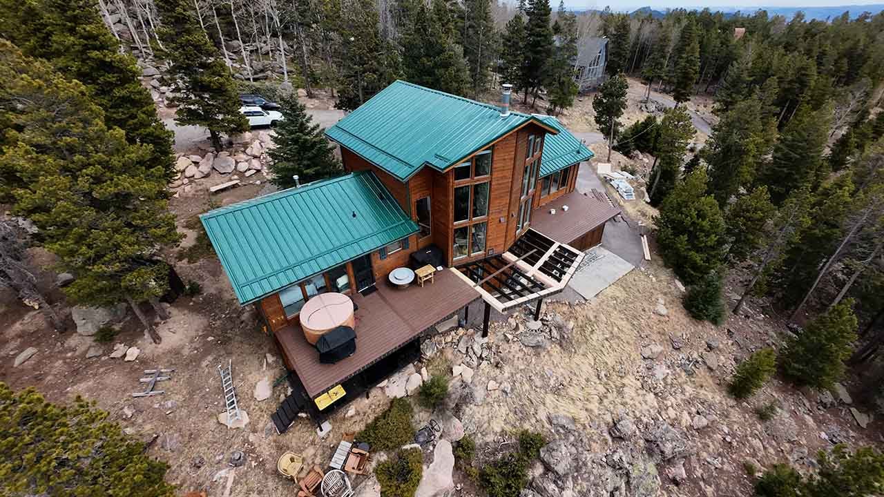 Drone photo of a beautiful colorado mountain home with a green pro panel metal roof