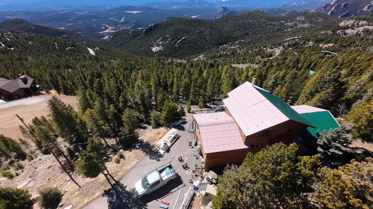 Drone photo of a beautiful colorado mountain home with a metal roof being installed