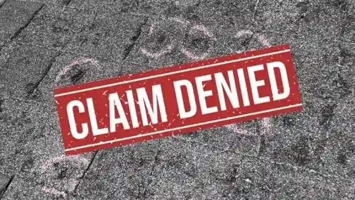 An asphalt shingle roof that is marked from a roof inspection, with a large red claim denied stamp on it