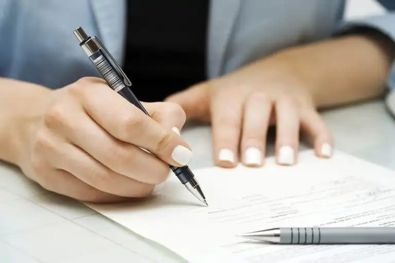 A person with white painted nails, going over their budget to finnd room for their roof replacement