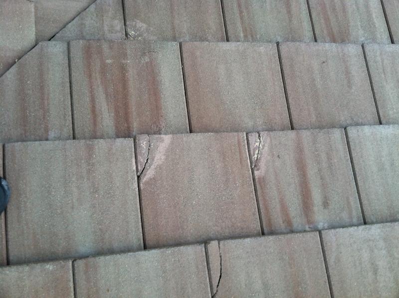 Square concrete tiles with many broken corners and iron colored efflorescence 