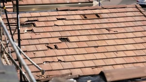 storm damaged red concrete tile roof, many tiles are shattered