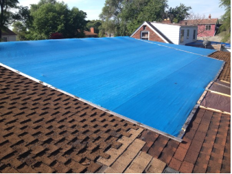 Wind damaged roof with blue tarp
